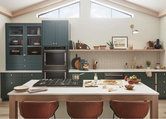 A modern, stylish kitchen with dark green cabinets and different ingredients that features a suite of KitchenAid® appliances.