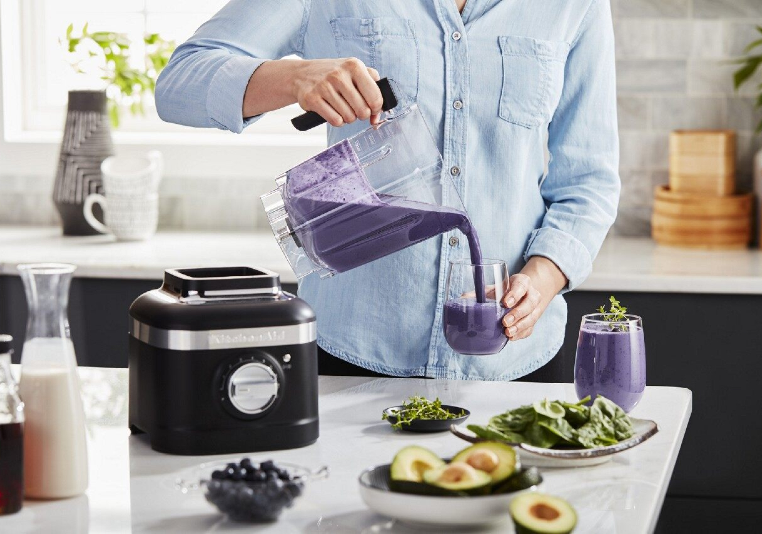 A person pouring a purple smoothie from a KitchenAid® blender. A person pouring a purple smoothie from a KitchenAid® blender.