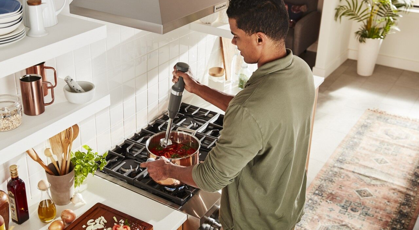 Same as Image Alt Text Person using immersion blender in pot on stove
