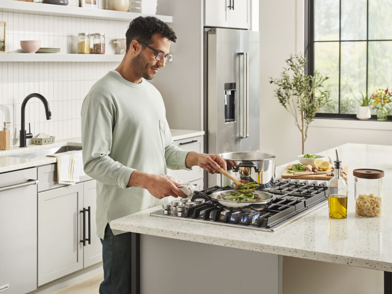 Person cooking on a gas cooktop Person cooking on a gas cooktop