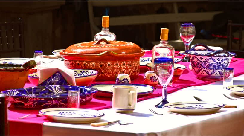 A table set with a fuchsia runner, colorful bowls and patterned dishware.