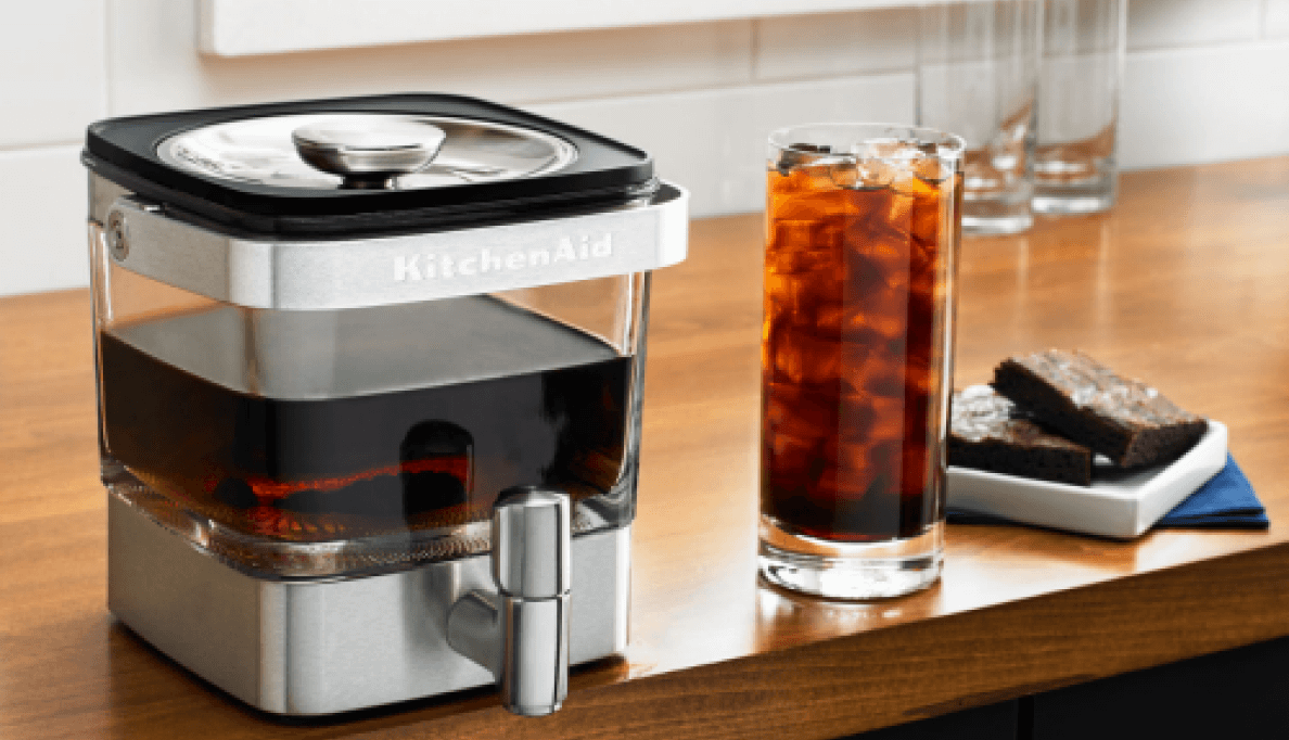 A glass of cold brew sitting next to a KitchenAid® Cold Brew Maker. 