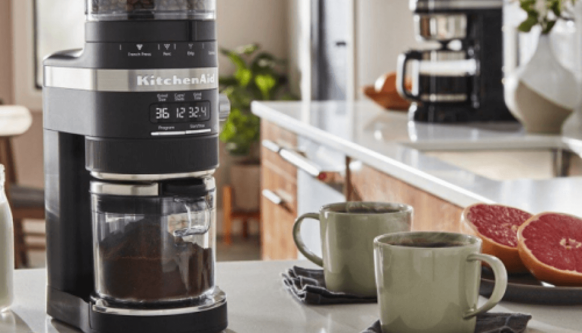 Best home coffee setup on countertop, including KitchenAid® Burr Grinder surrounded by milk, cinnamon, two cups of coffee and grapefruit.