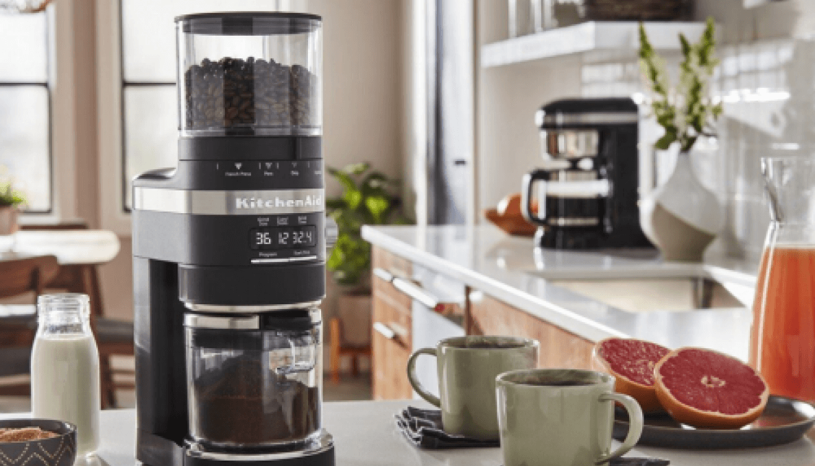 Best home coffee setup on countertop, including KitchenAid® Burr Grinder surrounded by milk, cinnamon, two cups of coffee and grapefruit.