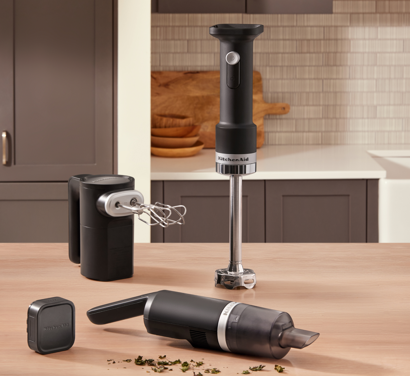 The KitchenAid® Go™ Cordless Hand Mixer, Hand Blender and Kitchen Vacuum sitting on the counter near dried herbs. 