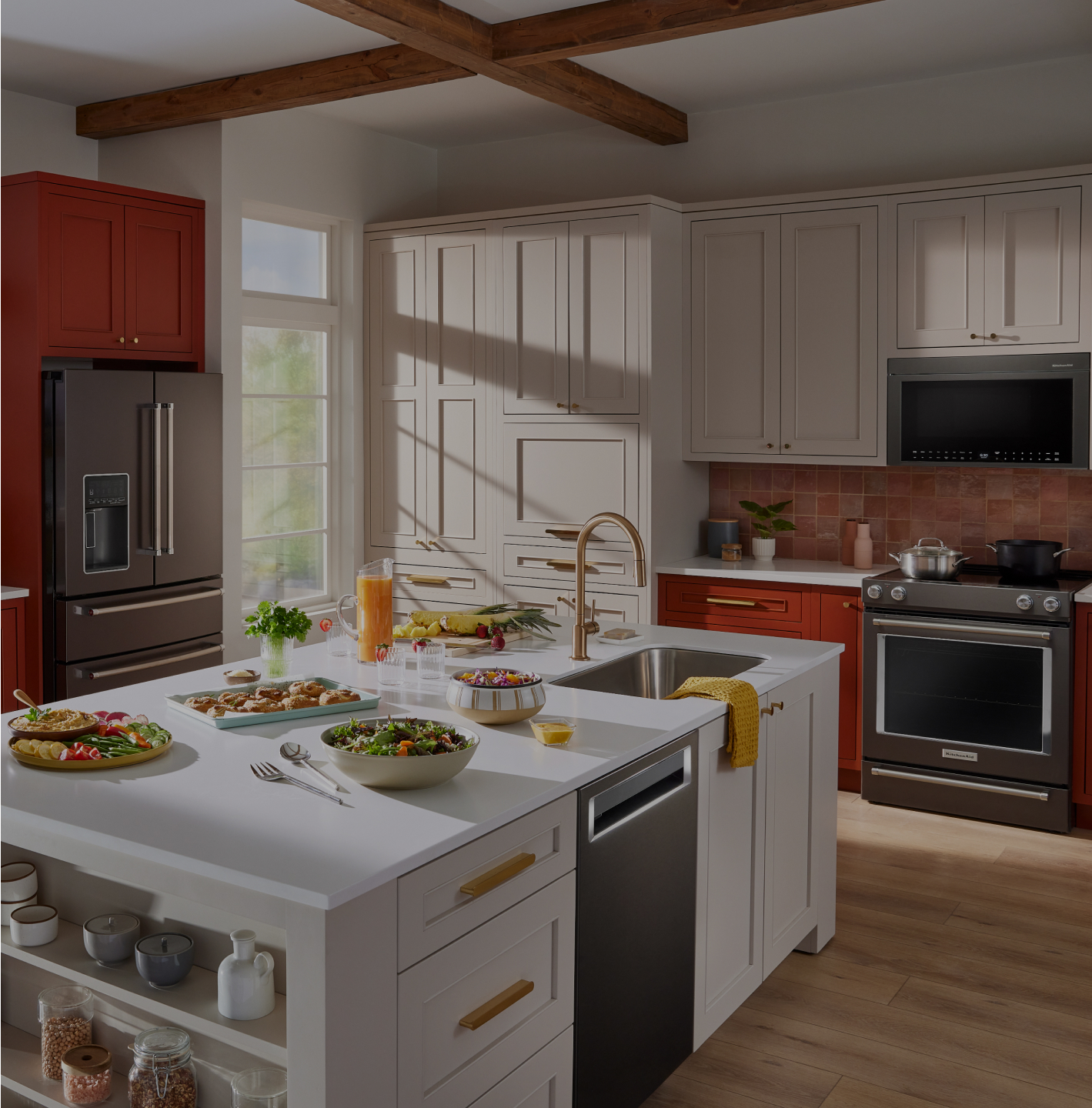 A bright, modern kitchen with red and white cabinets filled with KitchenAid® appliances.