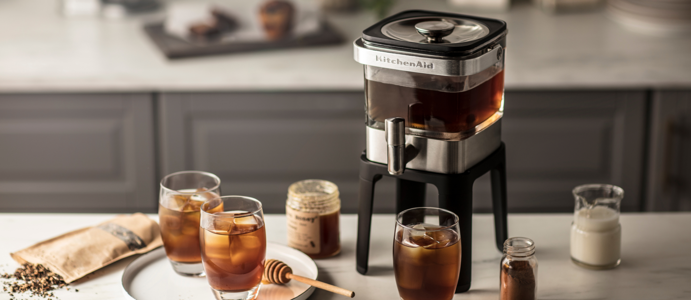 A KitchenAid® cold brew maker surrounded by glasses of cold brew.