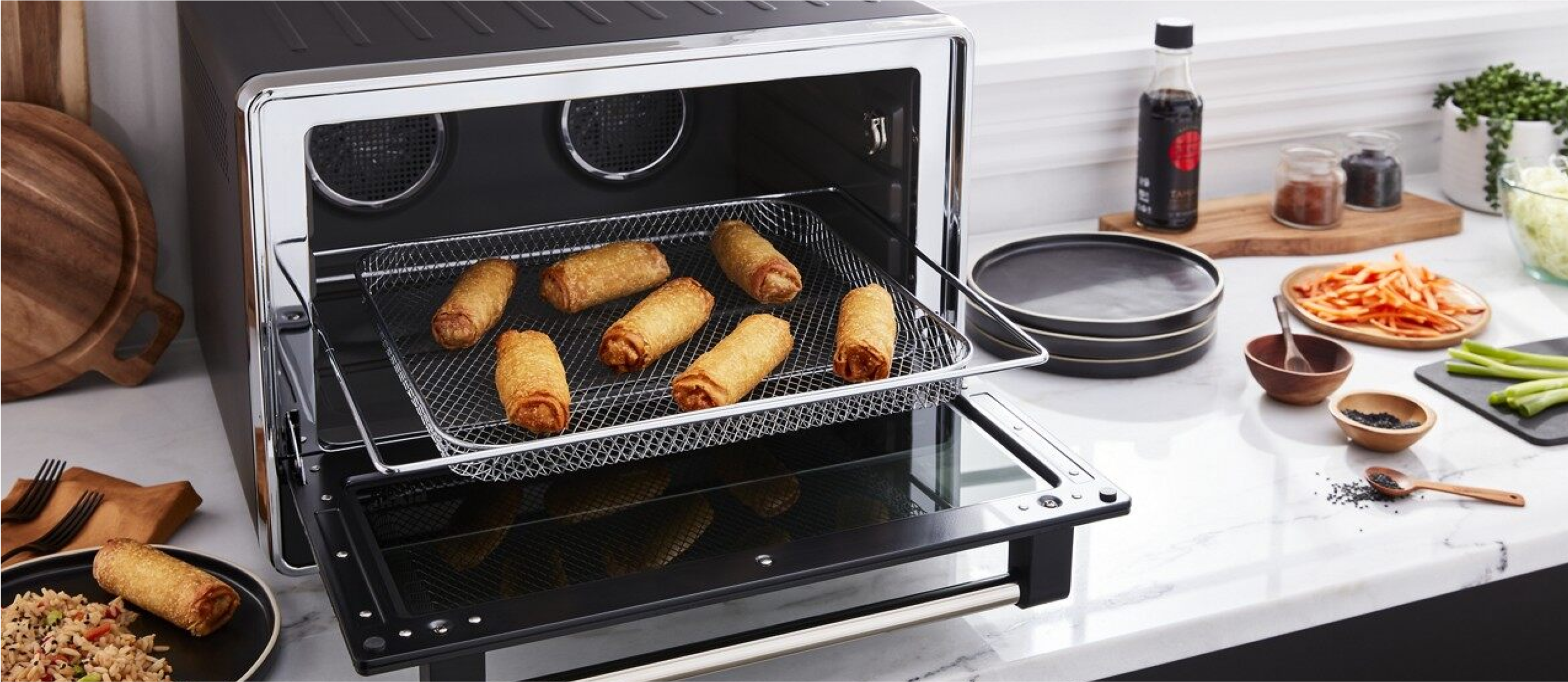 A KtichenAid dual convection countertop cooking egg rolls.