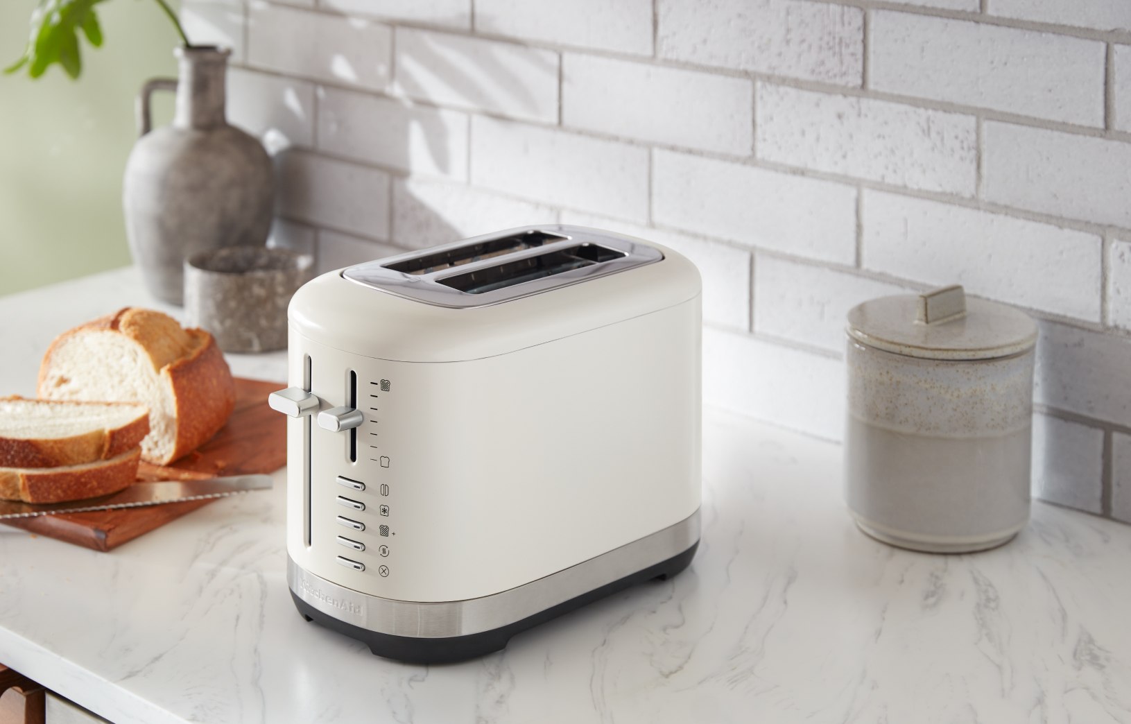 A KitchenAid® 2-Slice Toaster next to sliced bread.