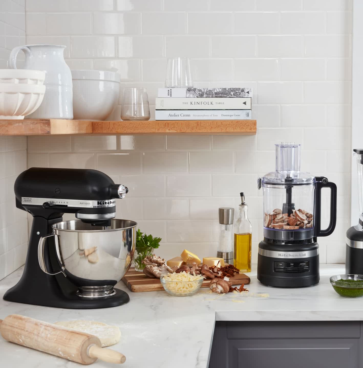 A KitchenAid® Stand Mixer and Food Processor in a crisp, stylish kitchen preparing fresh ingredients.