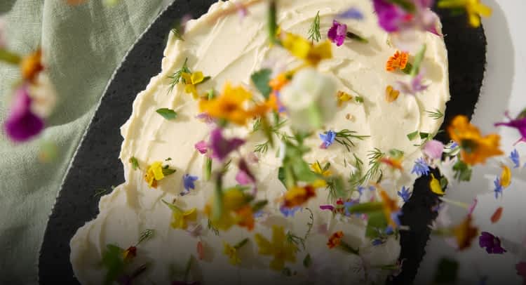 Edible flower petals being sprinkled onto butter.