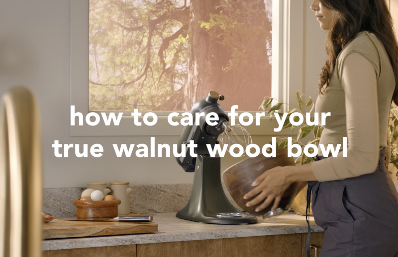 A person holding the true walnut bowl of the Evergreen stand mixer