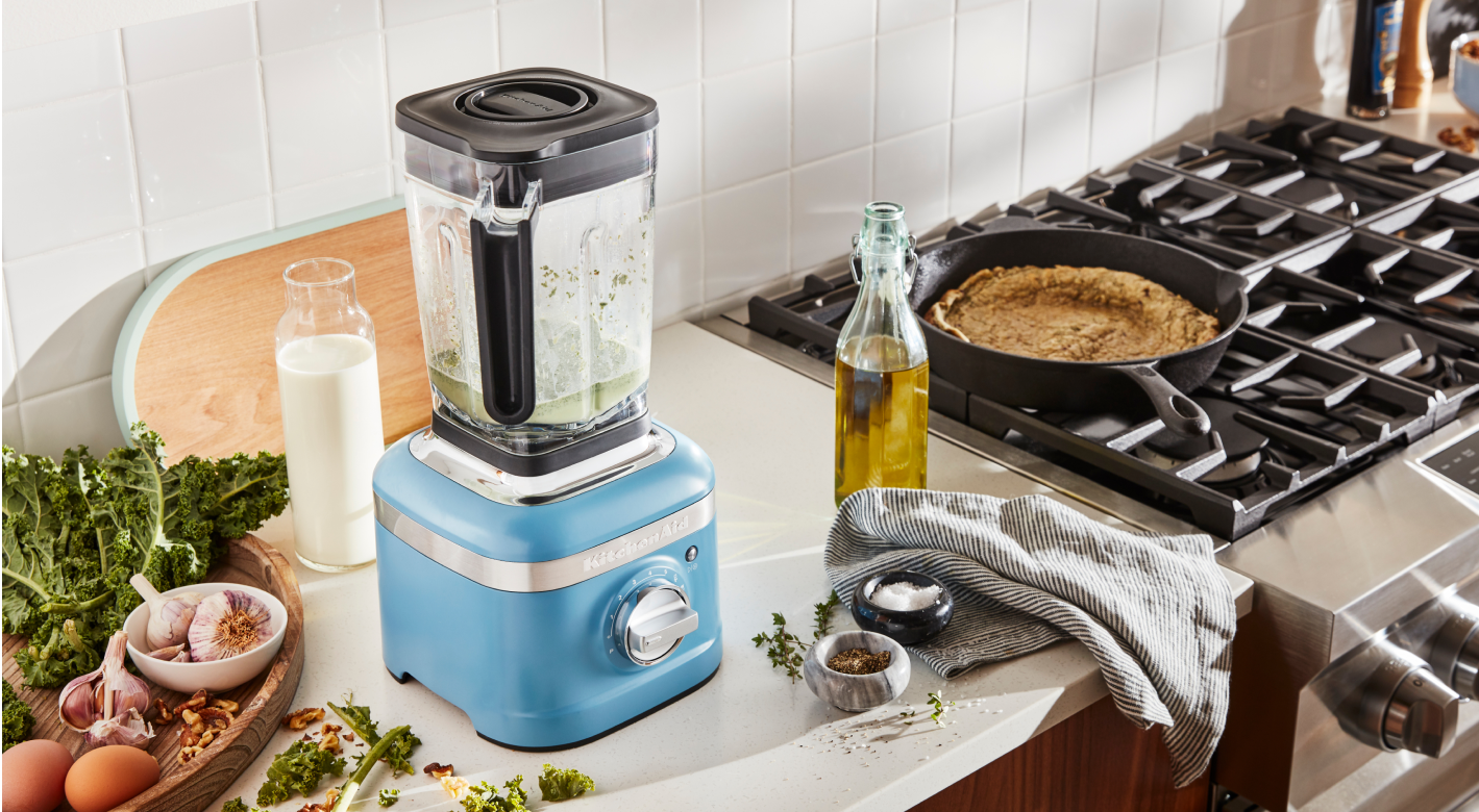 A KitchenAid blender next to a gas stove.