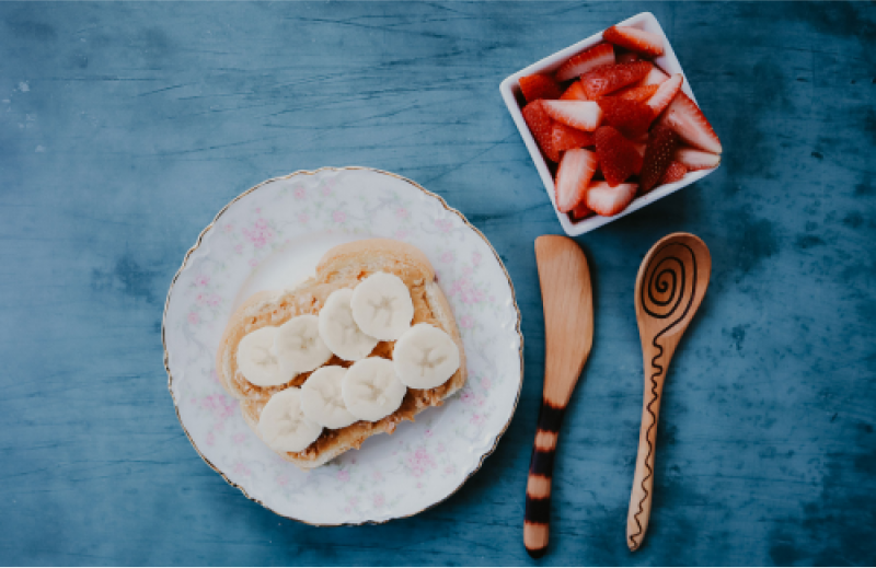 A piece of peanut butter toast with bananas and strawberries.