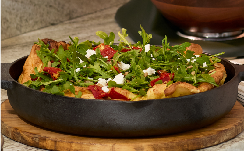 A savory dutch baby filled with a baby arugula salad.