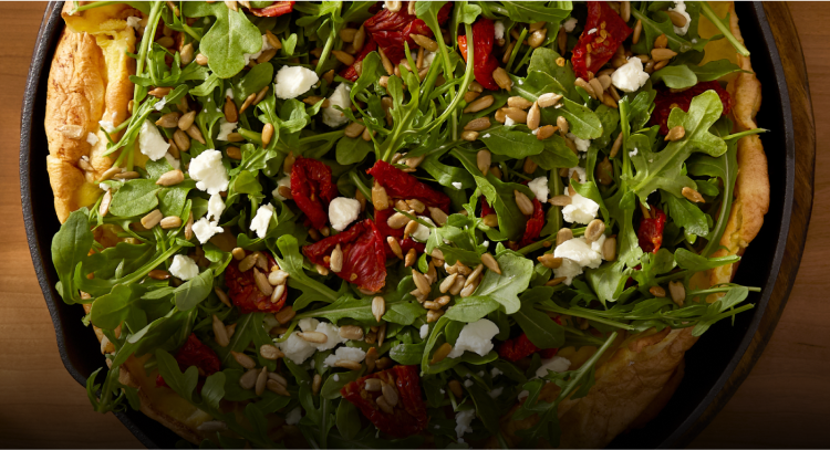 A savory dutch baby filled with a baby arugula salad.