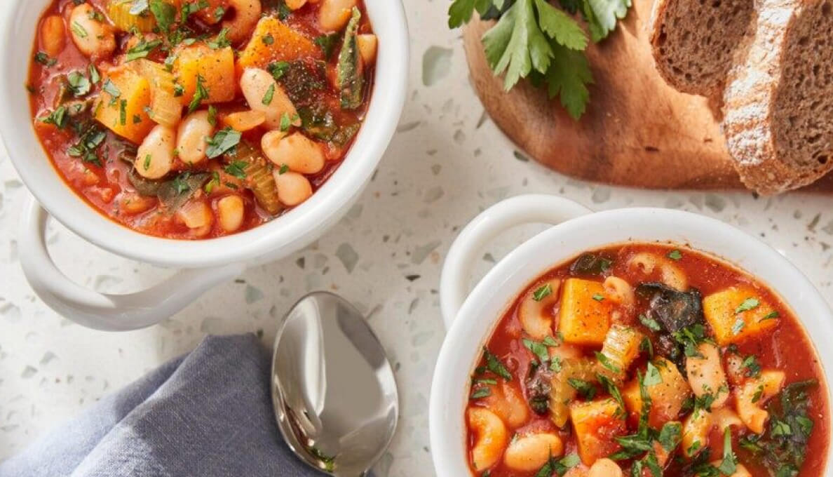 Two bowls of Pasta Fagioli sitting next to dark rye bread.