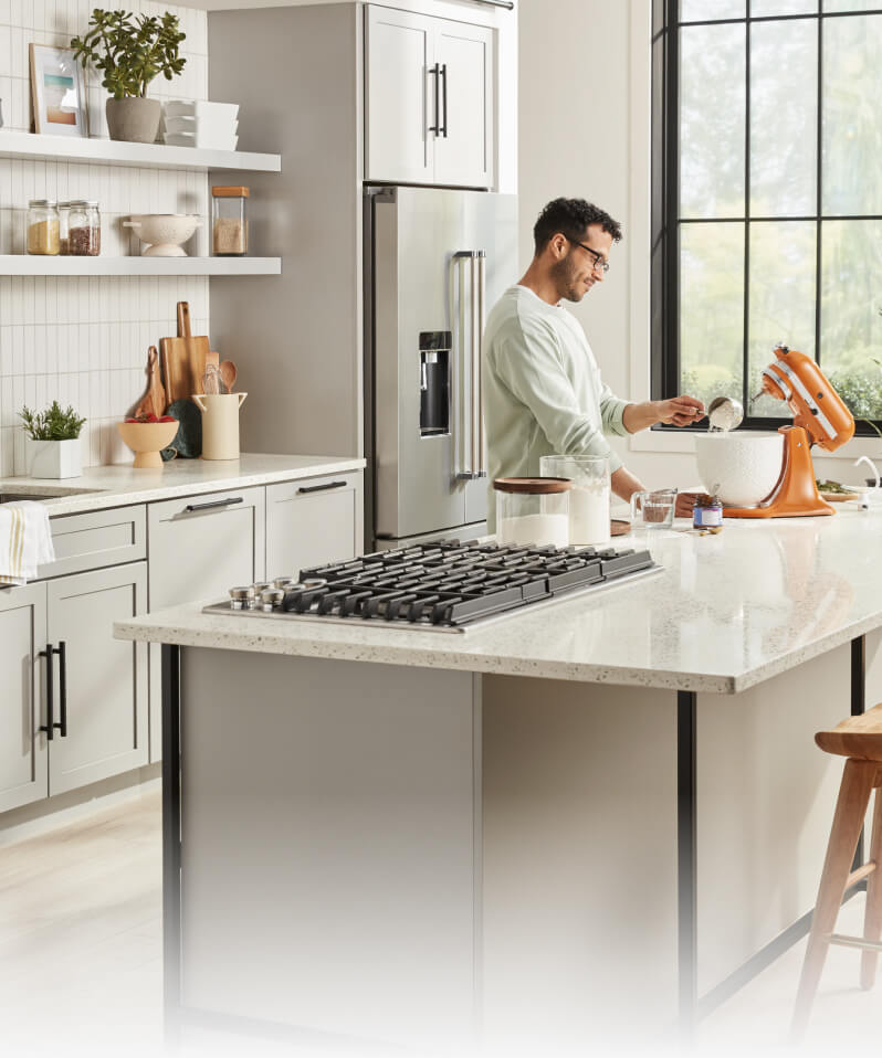 A person in a white kitchen using a KitchenAid® Stand Mixer
