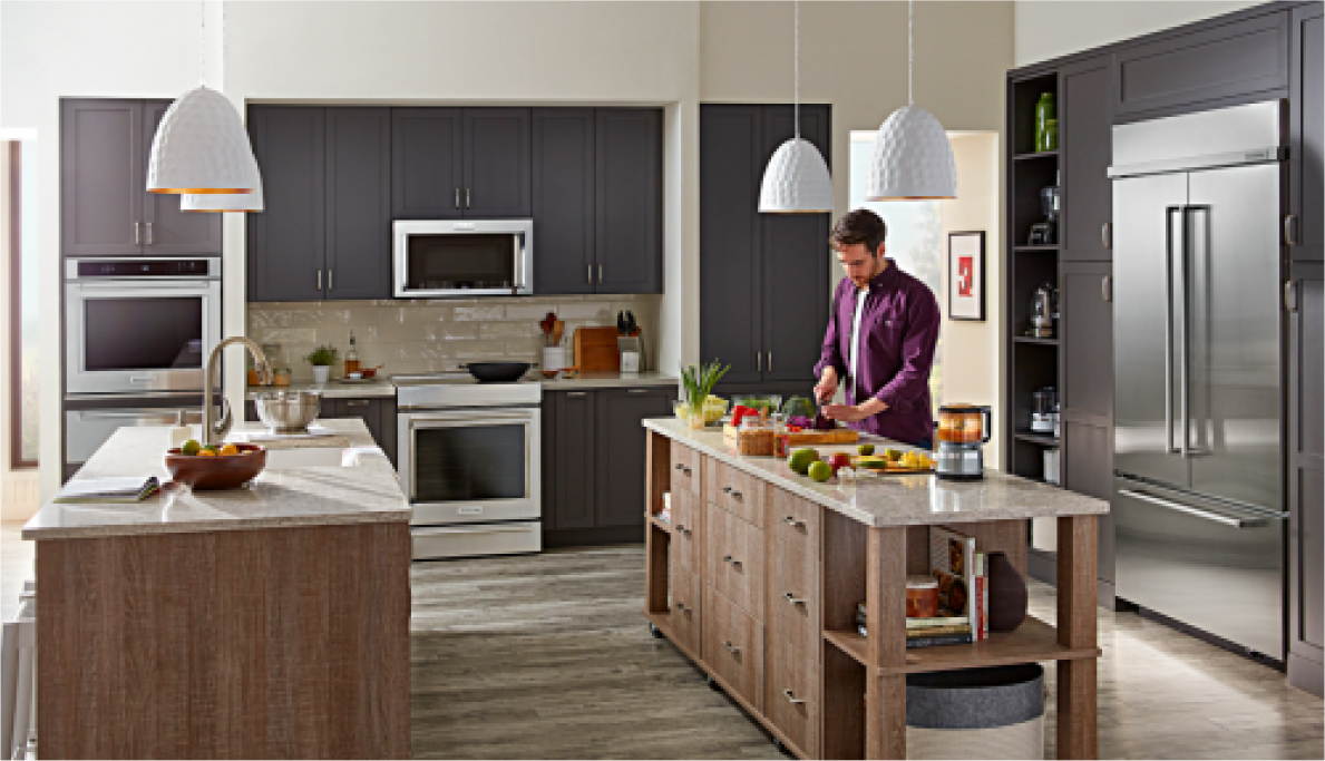 A person cooking at one of the double islands in a kitchen filled with KitchenAid® appliances.