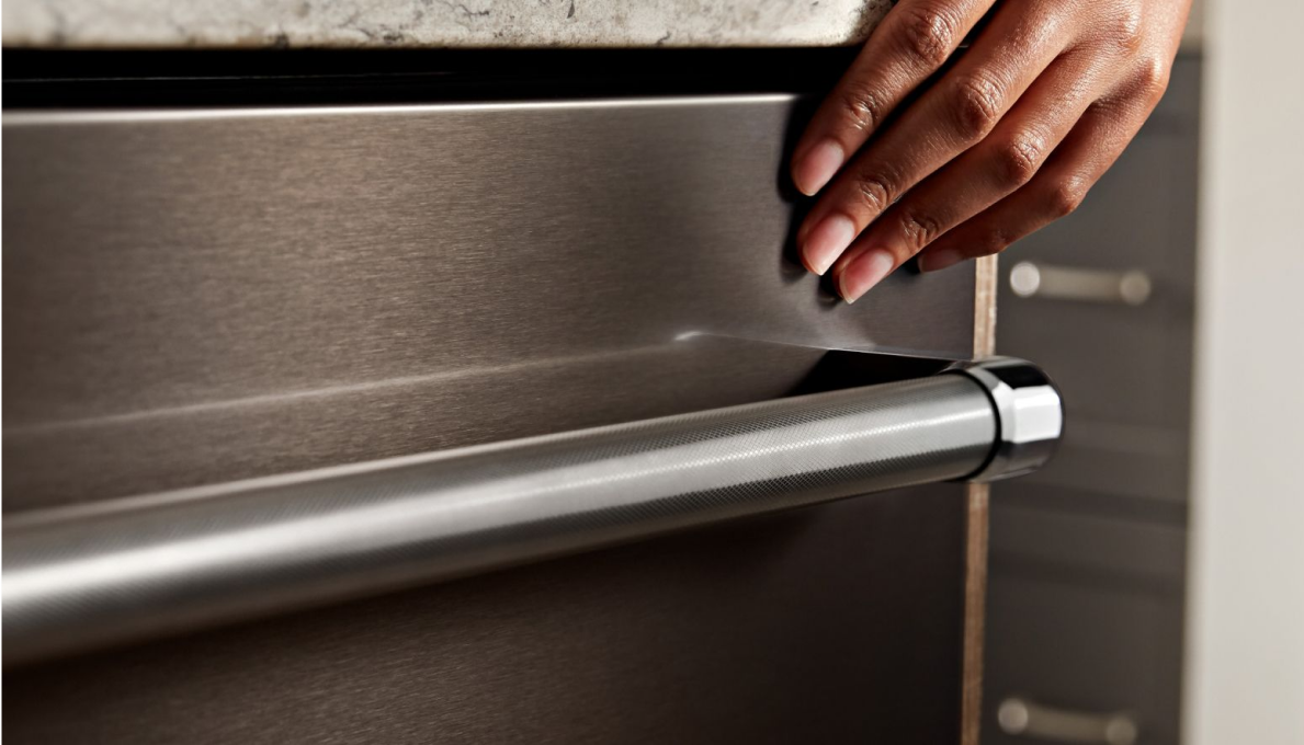 A person touching the exterior of a dishwasher.