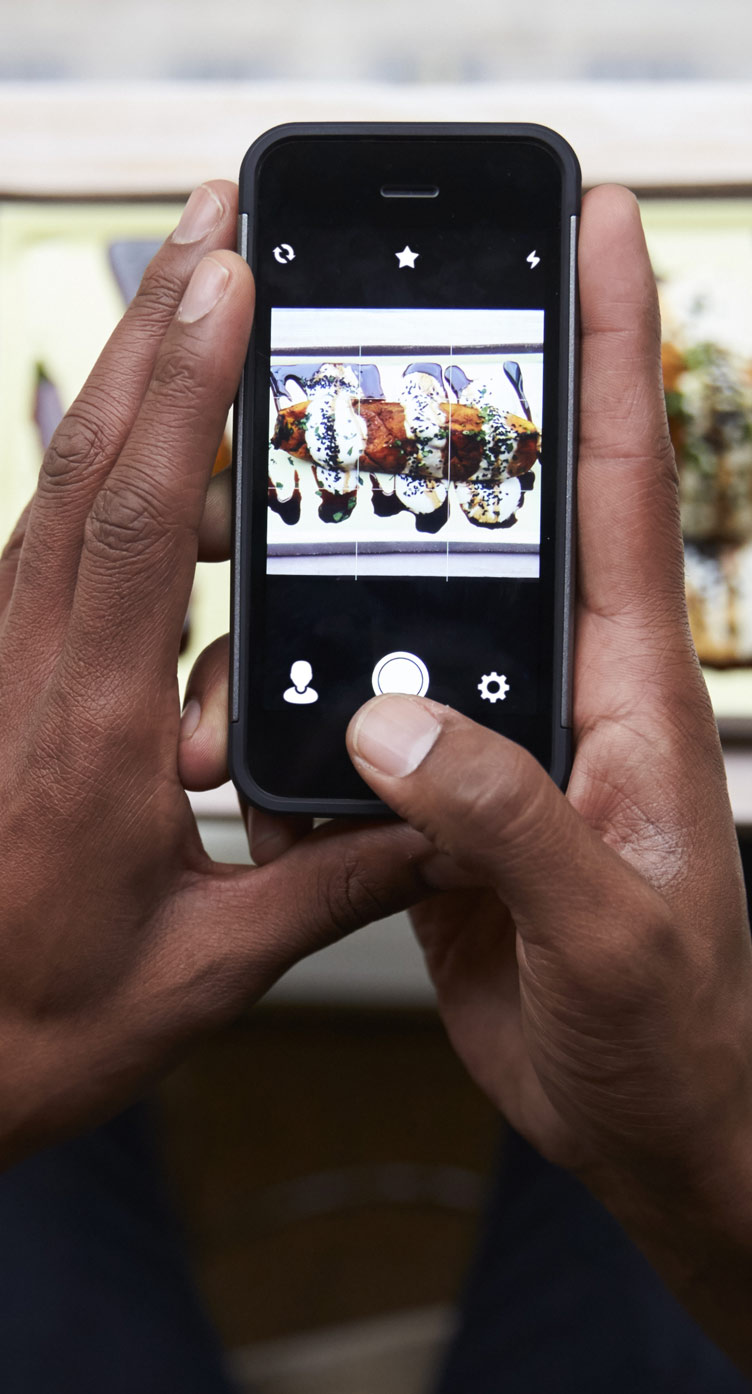 A young man taking a picture of his freshly made creation, a recipe made from scratch.