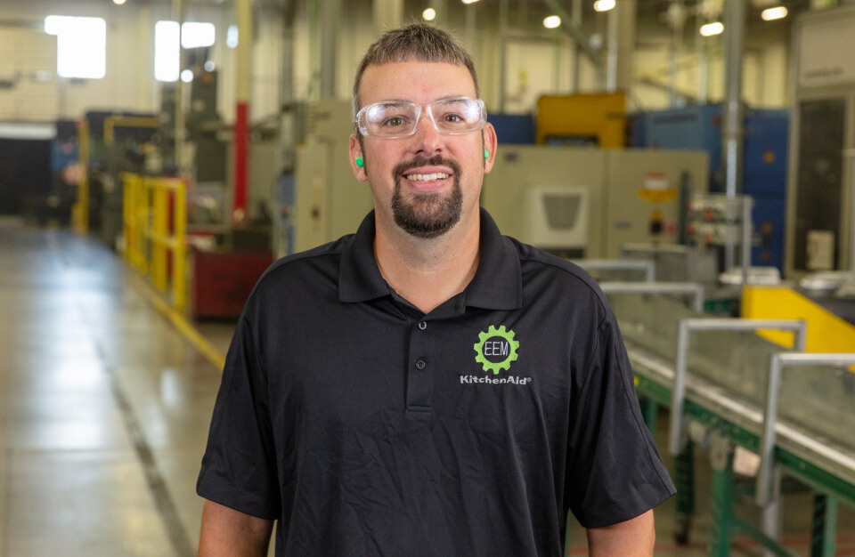 Smiling KitchenAid® employee at refurbished appliances facility.