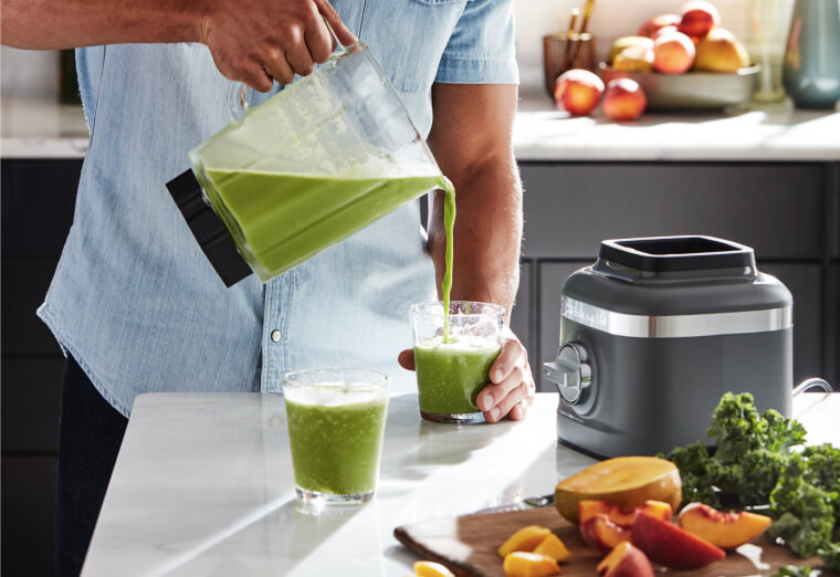 Man pouring a green smoothie from a KitchenAid® refurbished blender jar.