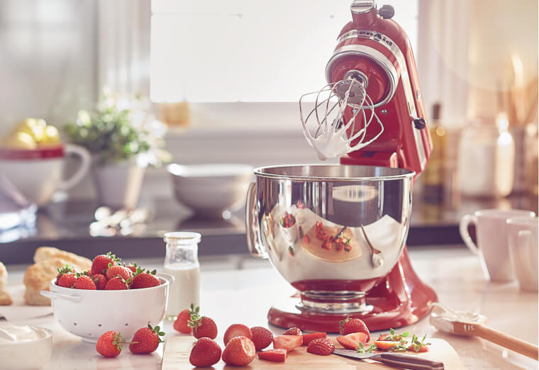 Refurbished KitchenAid® mixer with wire whip and stainless steel bowl making whipped cream.