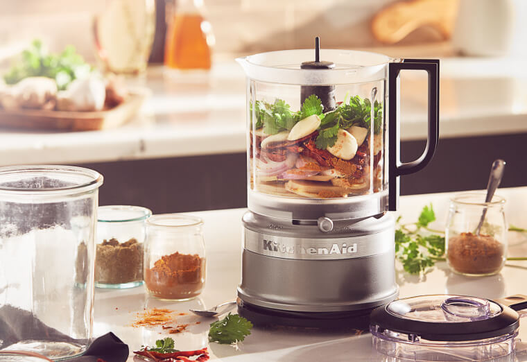 Silver refurbished food processor filled with ingredients.