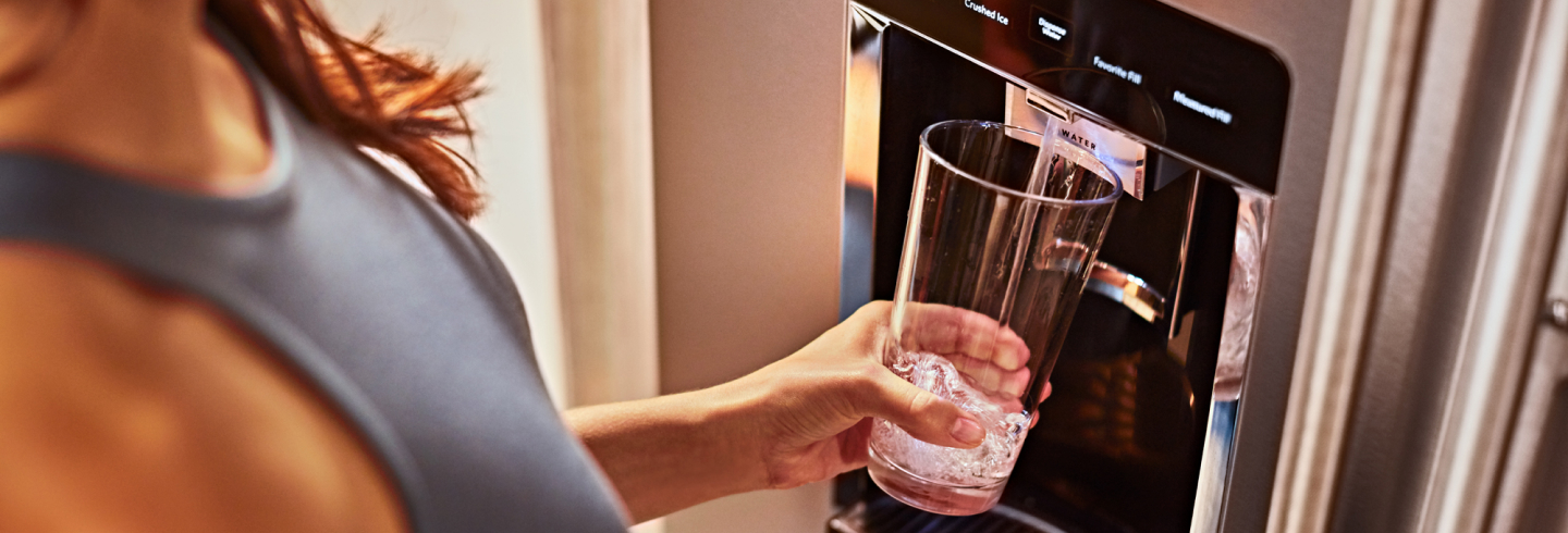 Filling a glass from a KitchenAid® refrigerator water dispenser.