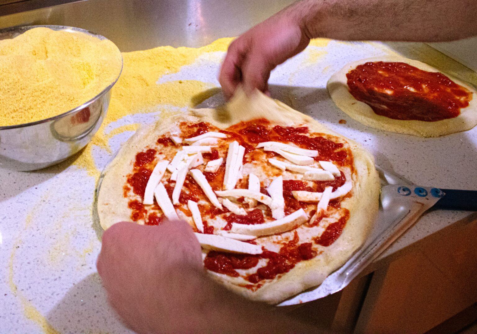 Experienced hands preparing a pizza from scratch.