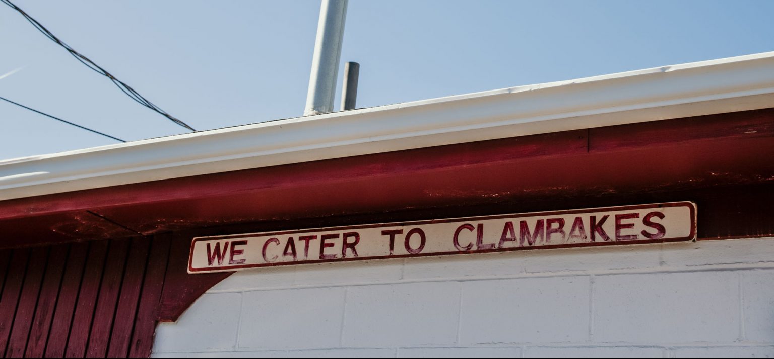 An old, faded sign of Woodman's Clam Strip.