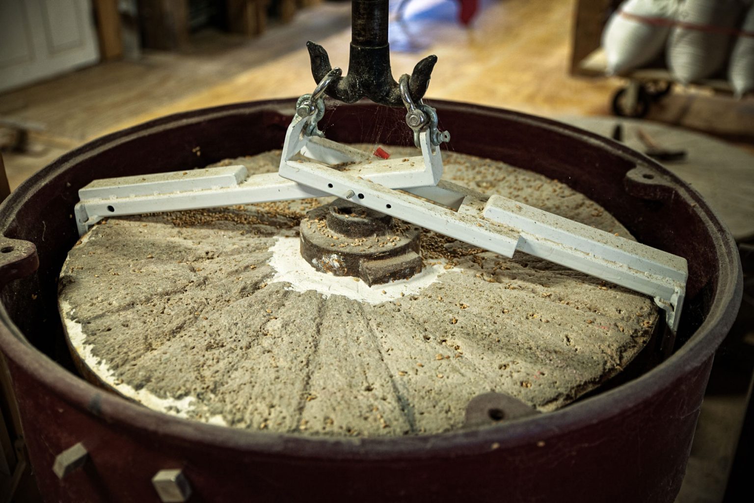 The heavy stone of a grain mill covered in residual grain.