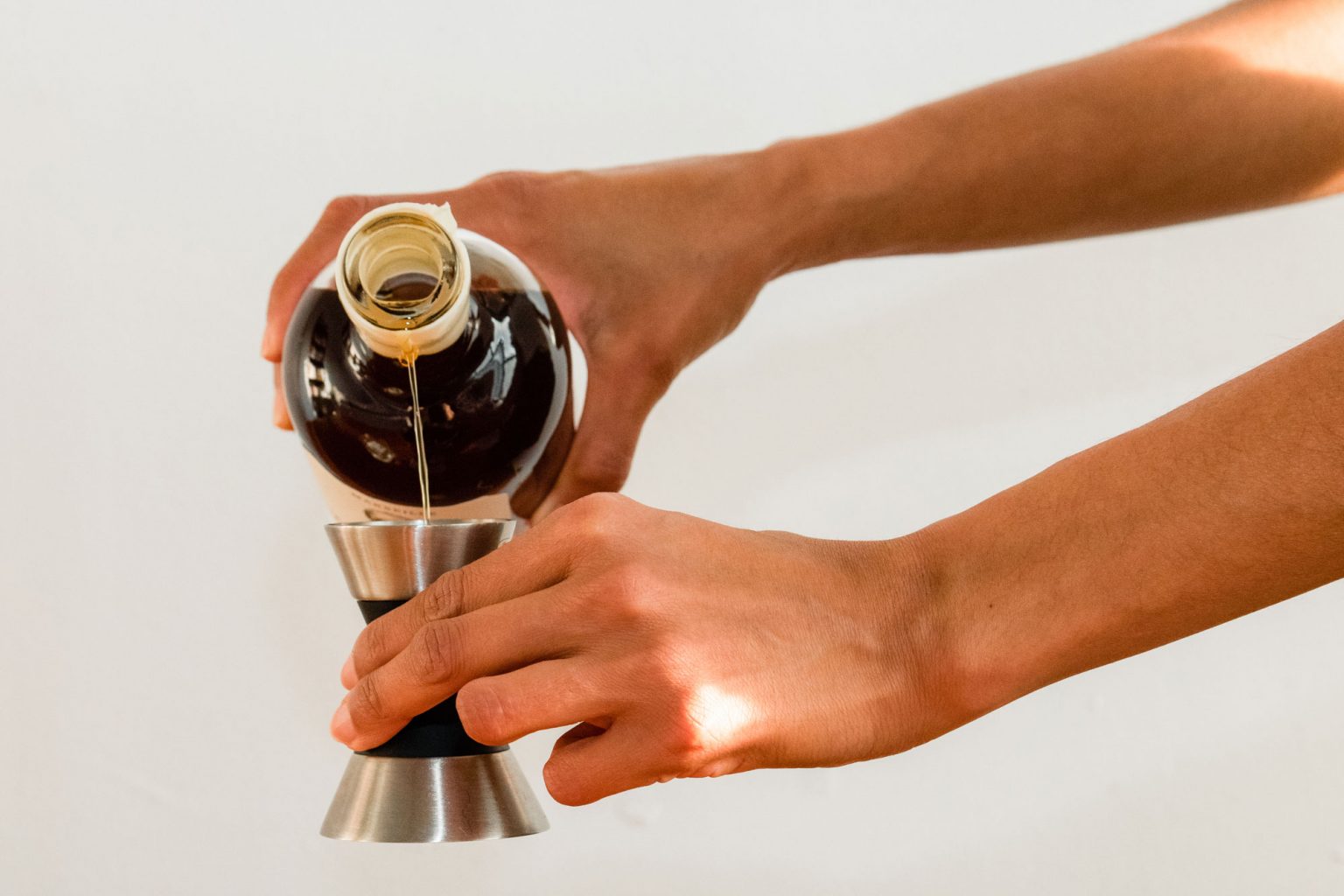 A person pouring Forthave Spirit liquor into a jigger.