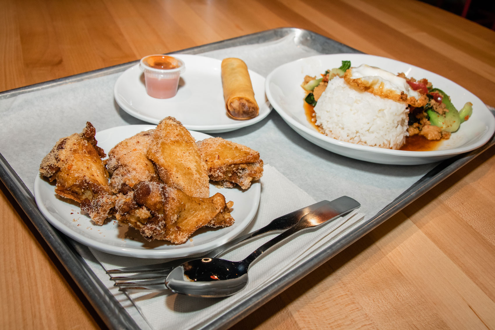 A tray of fried chicken wings and Thai food.