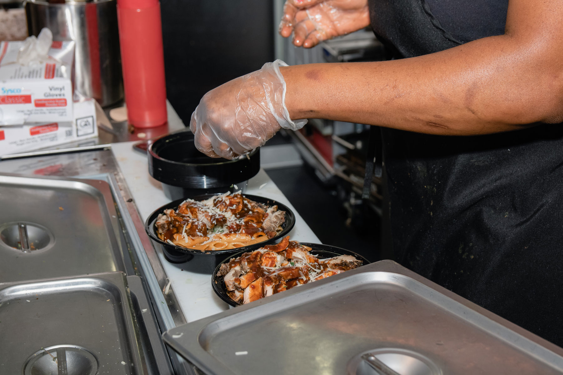 A person serving containers of Jamaican food.