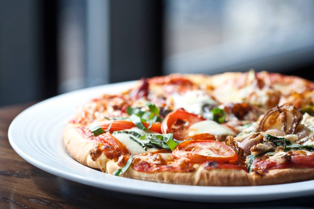 A freshly made pizza cooling off on a clean, white plate.