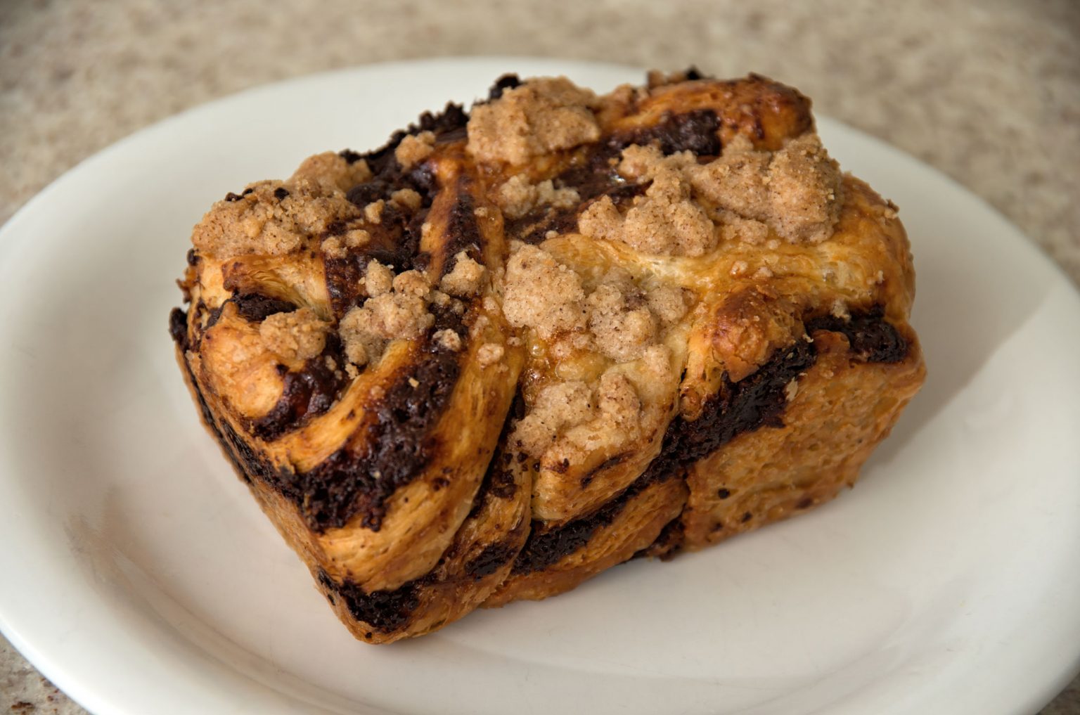 Chocolate babka bread on a clean, white plate.