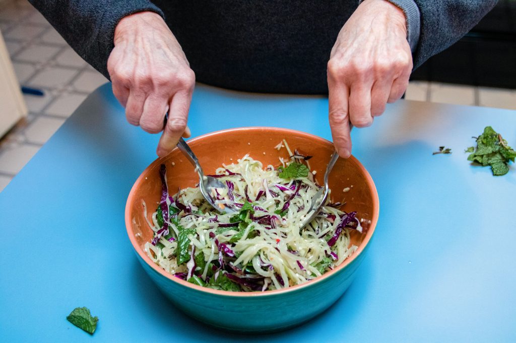 A person mixing together Spicy Green Papaya Slaw from Myers + Chang.