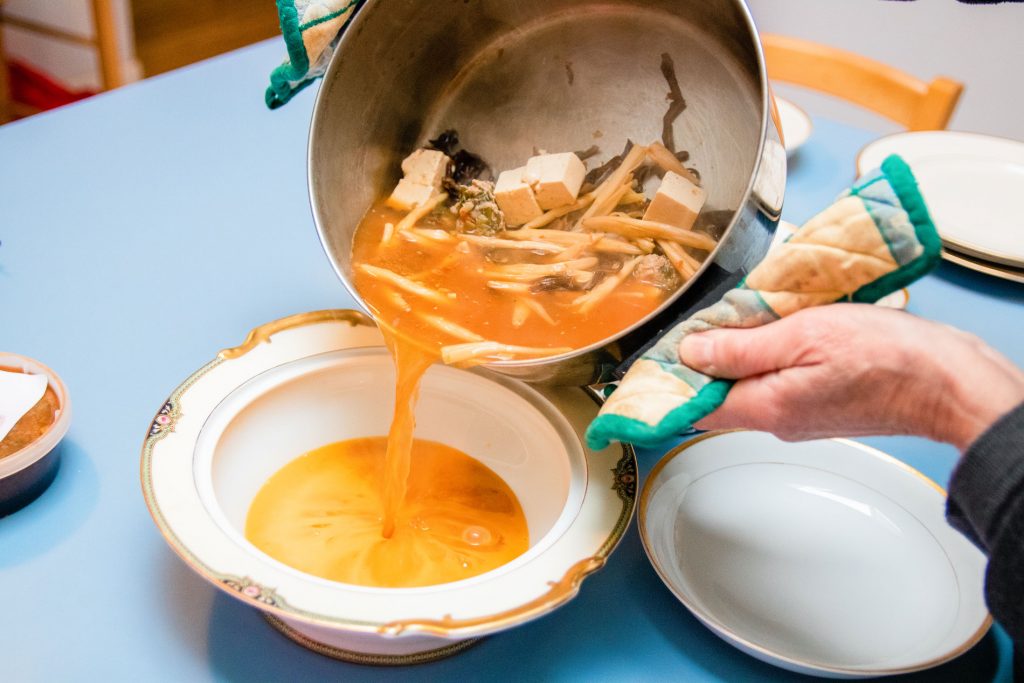 A person making take-and-make kit of soup.