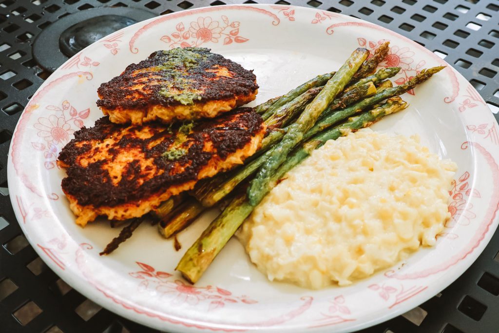 An ornate dinner plate filled with freshly cooked meat, asparagus and other sides.