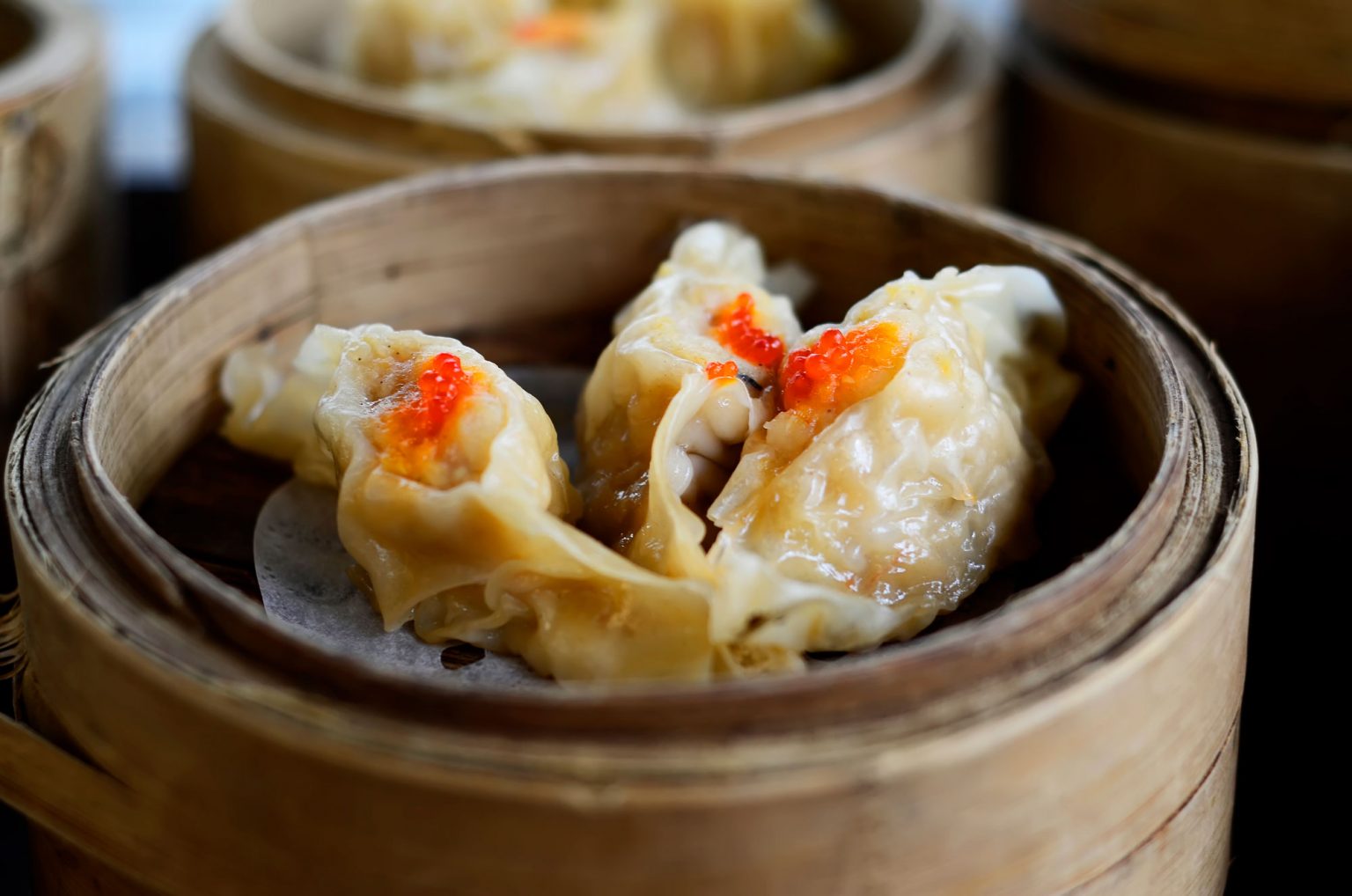 A small containter filled with three fresh dumplings.