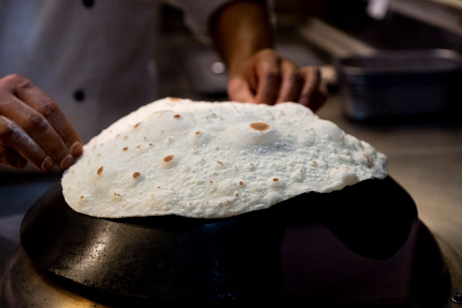 A person cooking paratha flat bread.