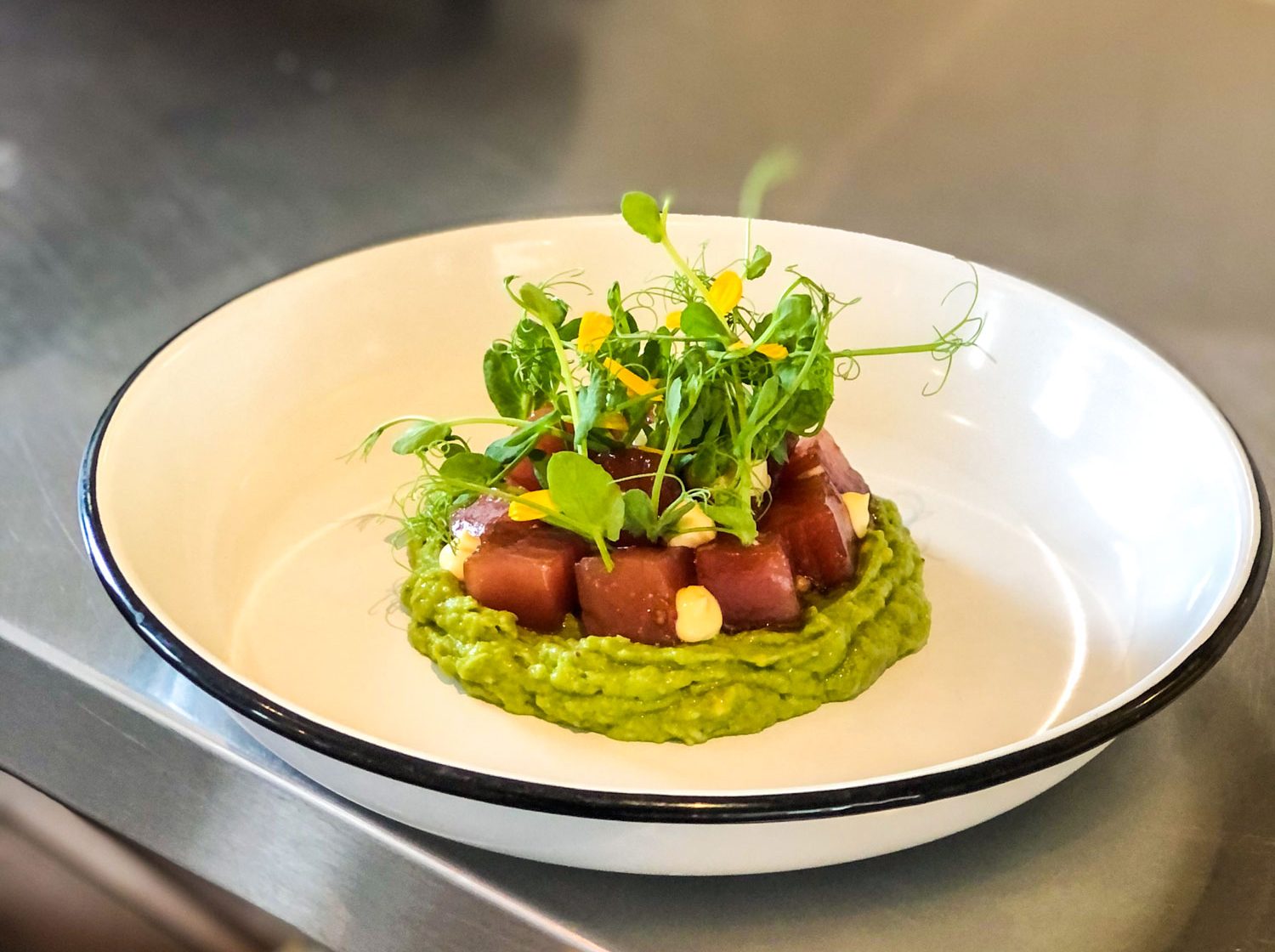 A fresh plate of ahi tuna resting on avocado.