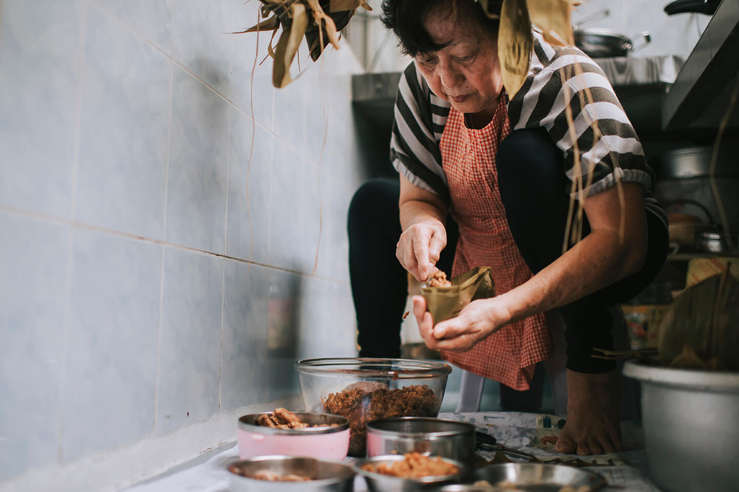 A woman stuffing rice into pocketed bamboo leaves.