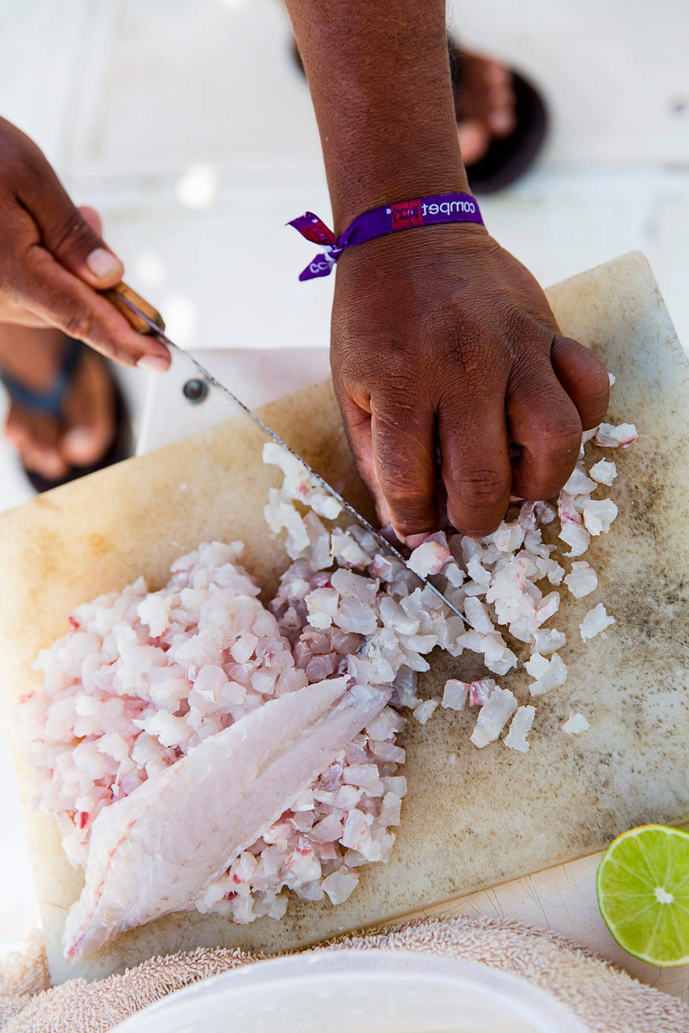 A person dicing up fresh fish on a wooden cutting.