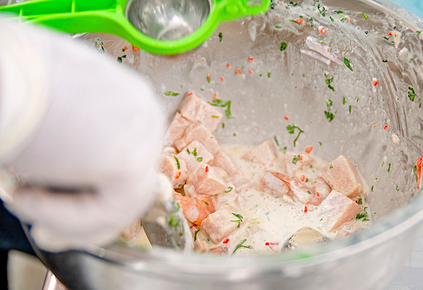Ceviche being freshly made and seasoned in a large glass bowl.