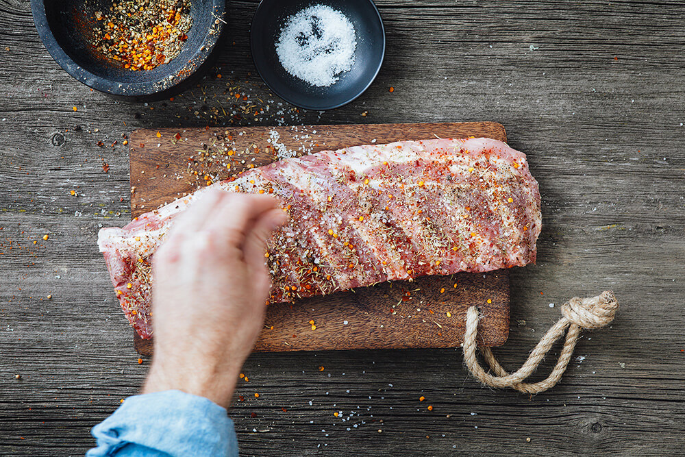 A rack of ribs sprinkled with various herbs and seasonings.