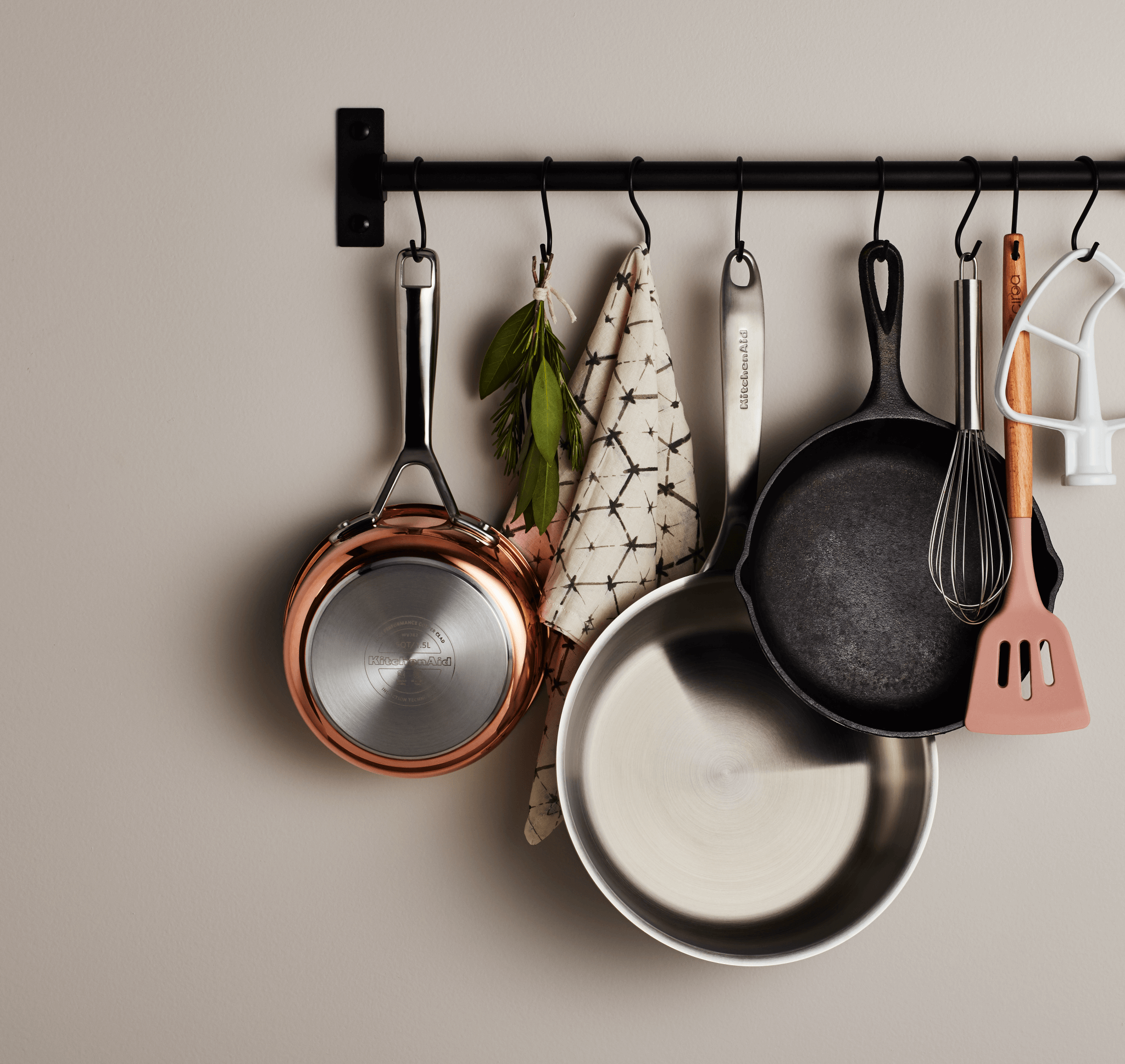 A collection of assorted pans and cookware hanging from a wall-mounted pot rack.