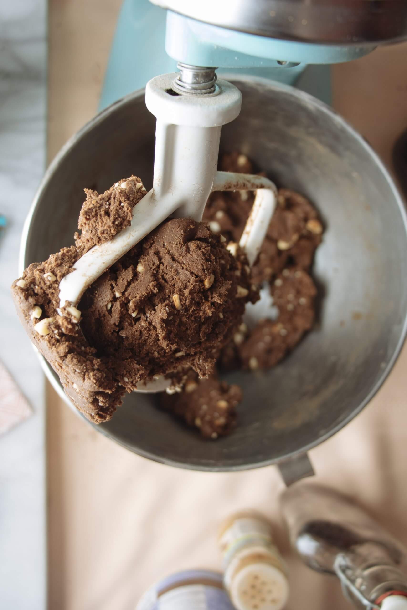 An overhead close-up of a mixer attachment doused in freshly made dough.